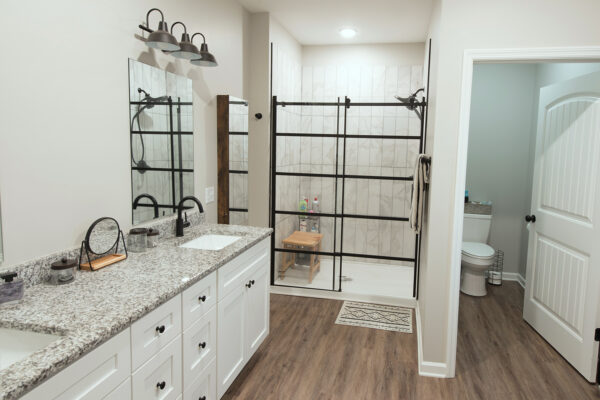 master bathroom with tiled walk-in shower, long his and hers vanity and water closet