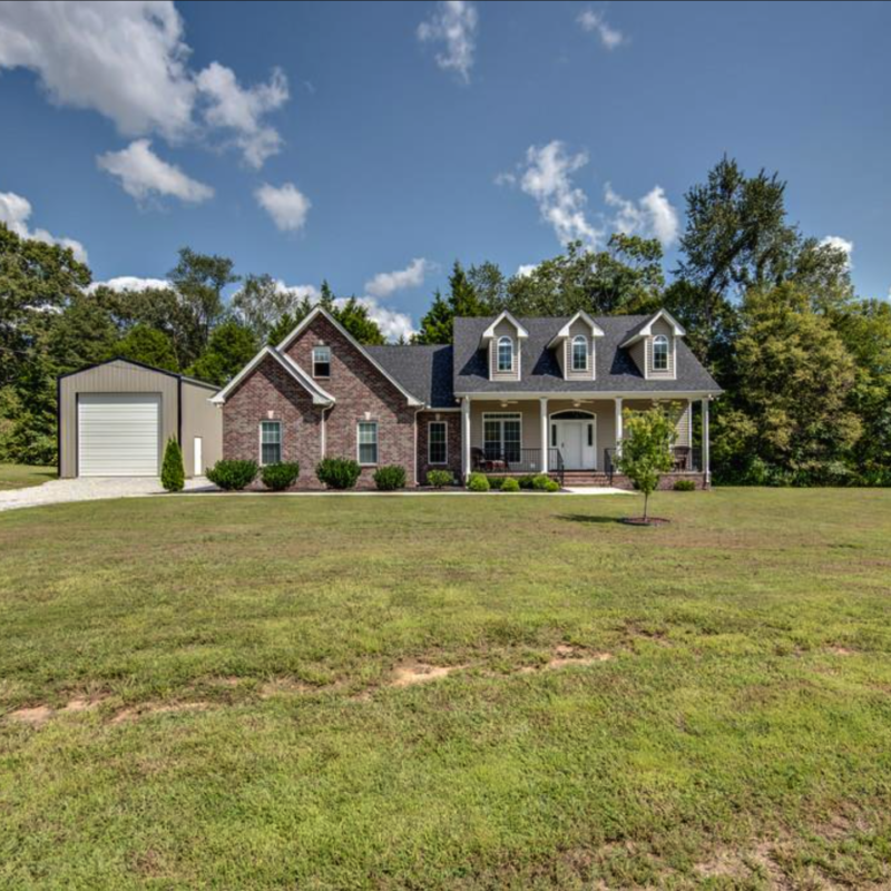 photo of a large brick home with dormer windows with a large front yard